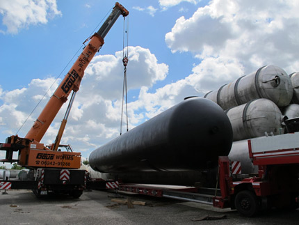 Kran hebt auf Freigel&auml;nde 170.000 Liter Retentionstank mit Bitumen-Anstrich f&uuml;r Erdeinbau auf LKW; im Hintergrund weitere Beh&auml;lter der Firma Tank und Apparate Barth GmbH